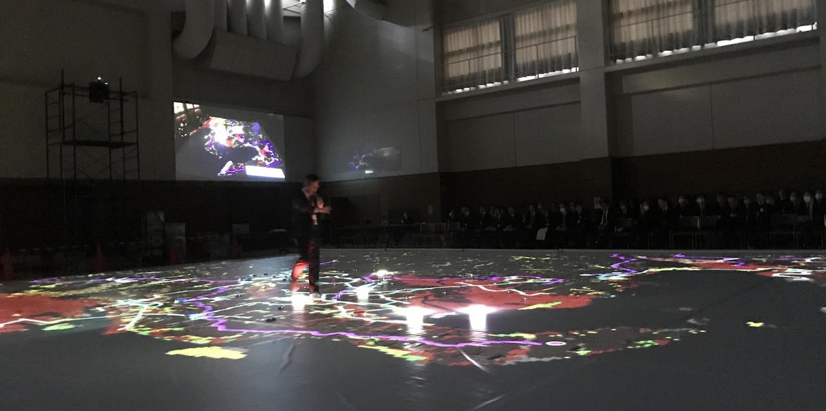 At the Nishi-Mikawa Disaster Prevention and Mitigation Research Committee workshop, participants spoke while walking on a map projected across the entire floor. (January 31 at the Nishio City Gymnasium)
