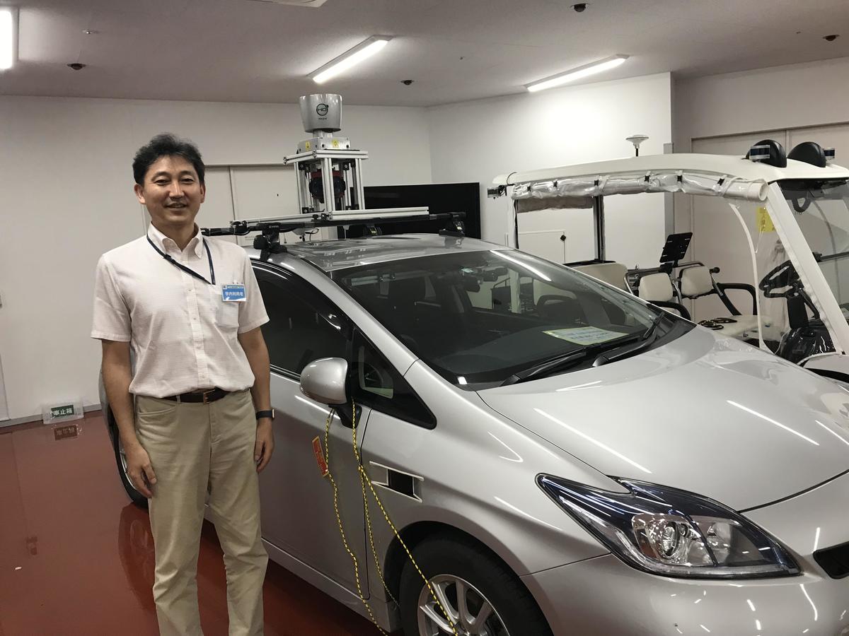 Designate Professor Hirofumi Aoki next to the experimental car