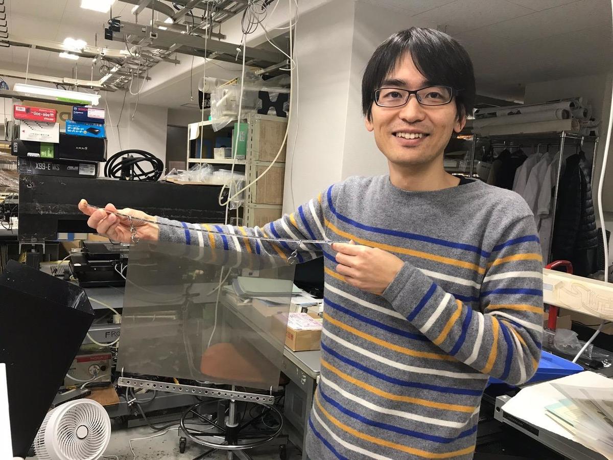 Designated Assistant Prof. Kunihiro Morishima showing a nuclear emulsion film