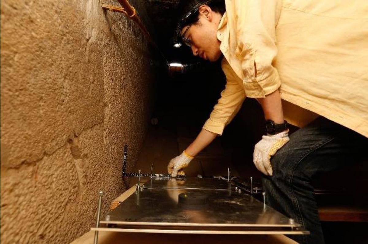 Morishima installing the detectors in the confined space. The nuclear emulsion films are sandwiched between two sheets of aluminum/