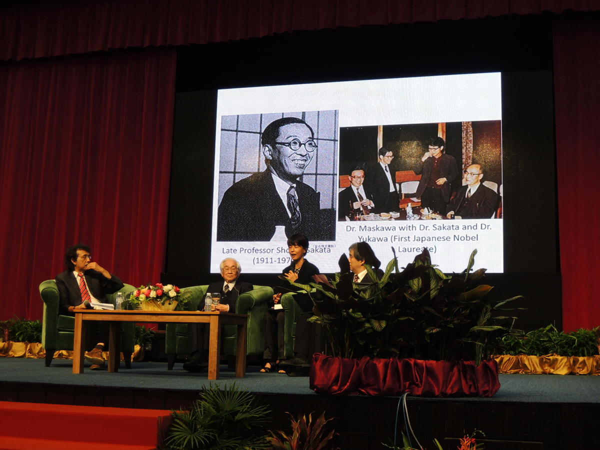Prof. Toshihide Maskawa speaking in front of a picture of Prof. Sakata, his university teacher
