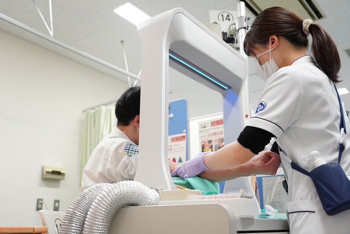 The desktop air curtain removes the need for a physical barrier, allowing easy physical contact between a doctor and patient, for example when drawing blood. (Credit: Junki Mikami)