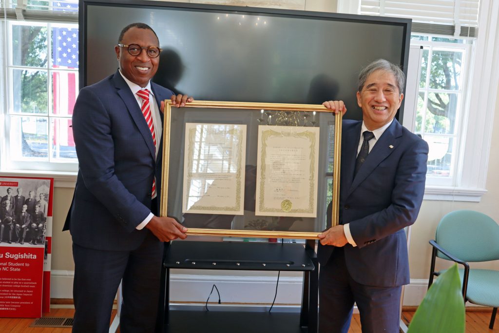 Nagoya University President Naoshi Sugiyama (right) and North Carolina State University Chancellor Kevin Howell (left) hold up a framed agreement of cooperation between the universities