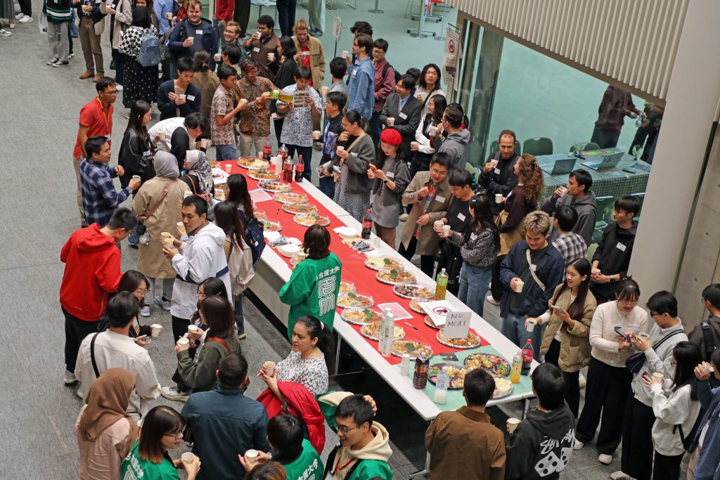 Students gather around tables lined with food and drink, preparing for a toast at the start of the Welcome Party 
