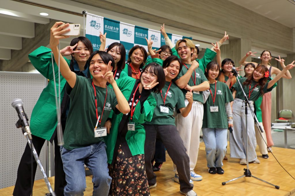 Student staff pose for a group selfie on stage towards the end of the party