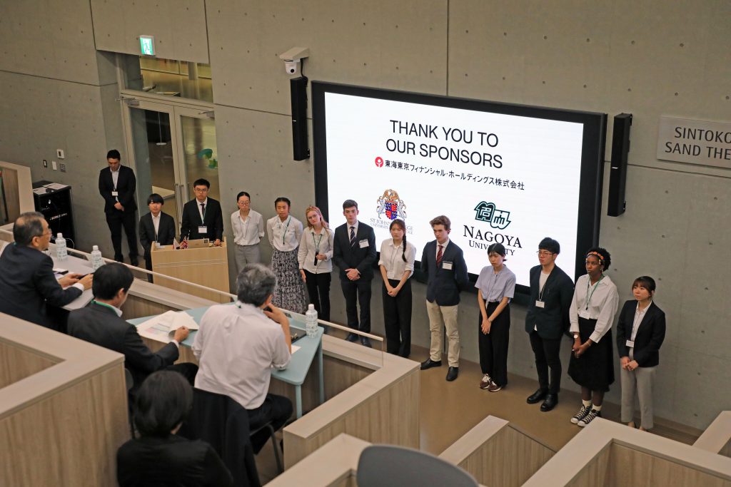 Students from Nagoya University and St John's College stand in a row at the front of the room, taking questions from the audience at the end of their research presentation.
