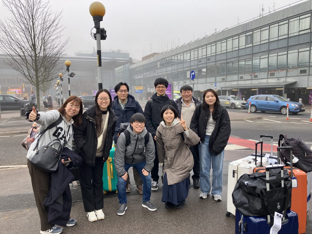The eight-person delegation from Nagoya University smiles for a photo after arriving in London on a dreary morning.
