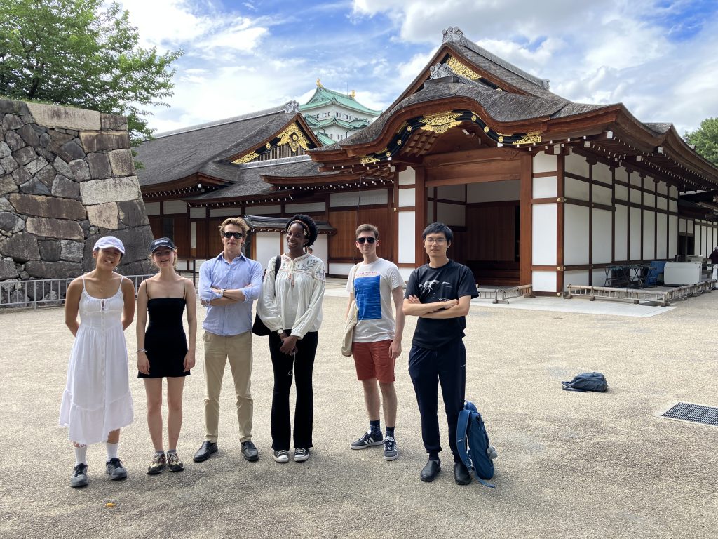 Six students from St John's College stand in front of Nagoya Castle.