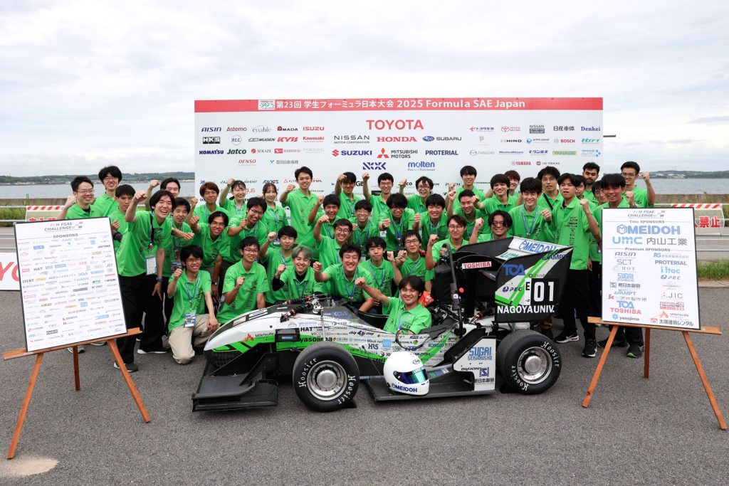 Members of Nagoya University Formula Team FEM stand in rows behind their formula car for a group photograph at the event.