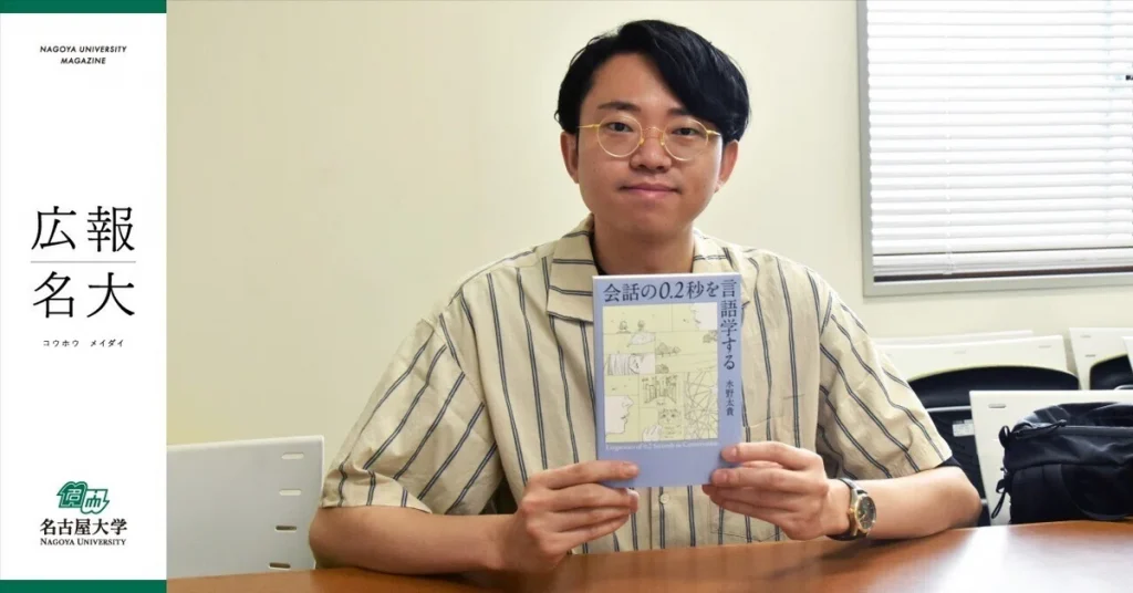 Daiki Mizuno, an alumnus from the Nagoya University School of Humanities, holds up a copy of his book.