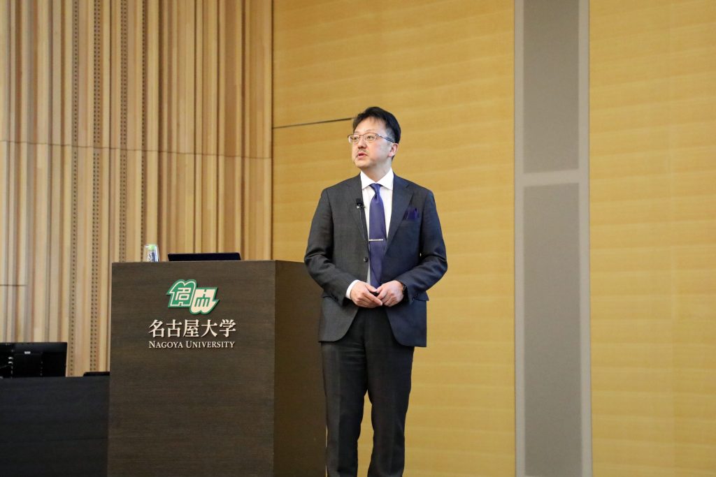 Professor Hajime Ito stands near a podium, giving one of his lectures during the event.