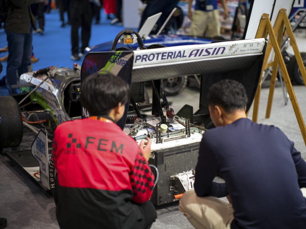 A Nagoya University student and an attendee look at the rear of the formula car.