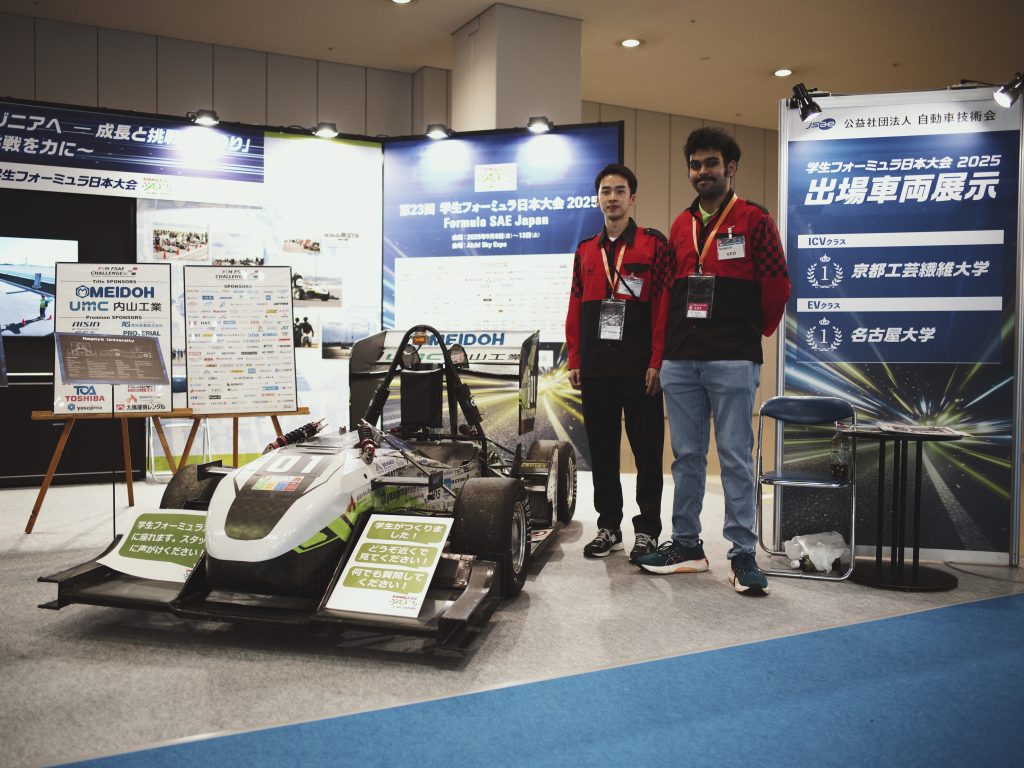 Two Nagoya University students stand next to their formula car.