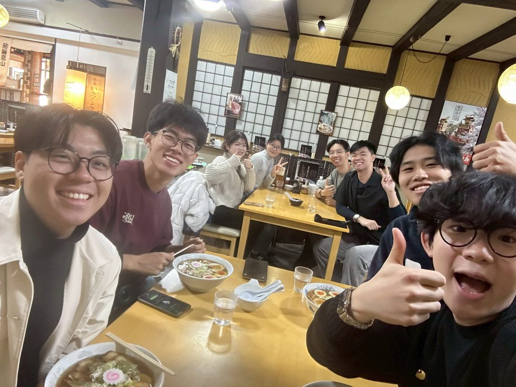Four students smile for the camera while sitting at a restaurant during the trip to Shirakawa-go.