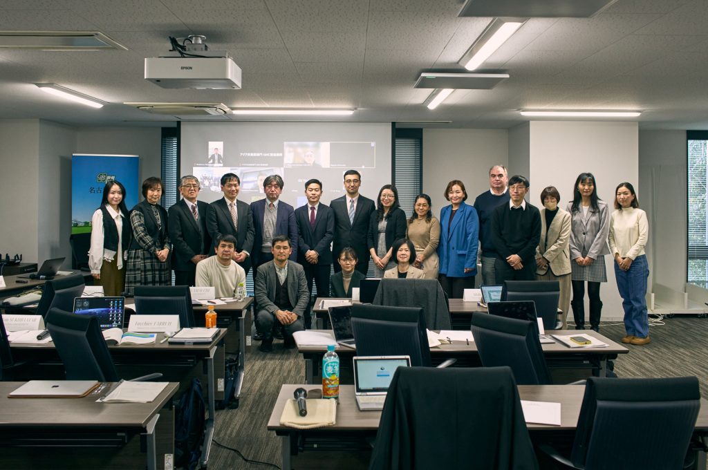 The participants stand in two rows for a group photograph at the front of the room.