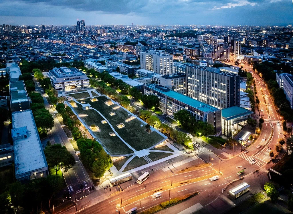 A photograph of ComoNe, the university, and the surrounding cityscape lit up at dusk.