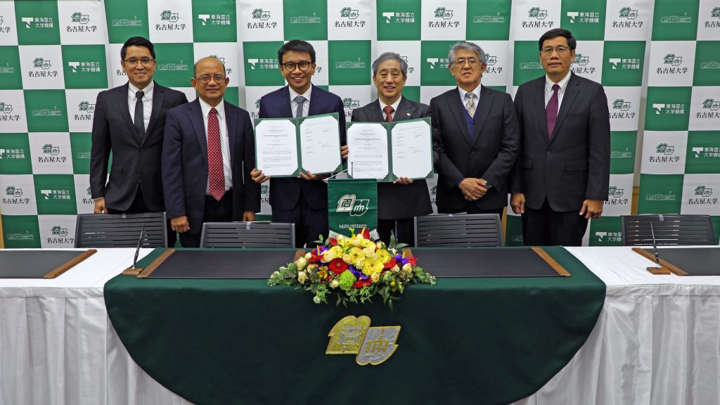 The signers stand in a row, holding the completed documents.