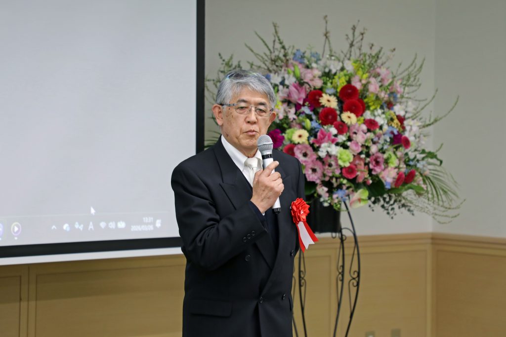 Akira Yamauchi stands at the front of the room and gives his remarks.