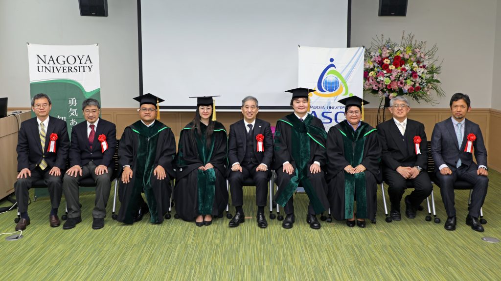 The graduate and guests of honor gather at the front of the room for a photograph.