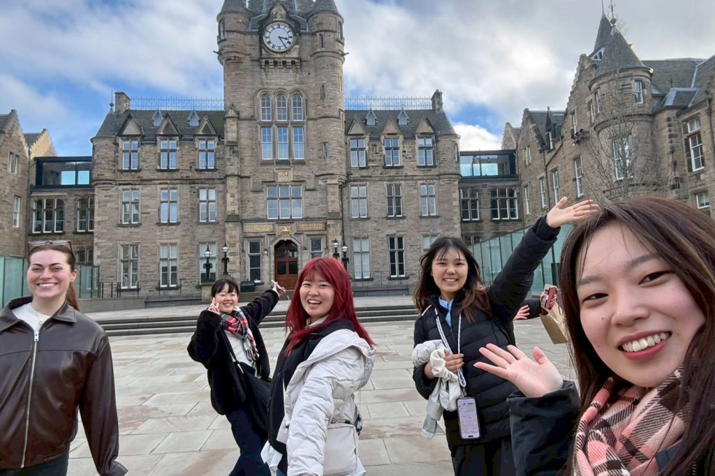 A group of female students from Nagoya University and the University of Edinburgh stand in front of one of the campus buildings in Edinburgh.