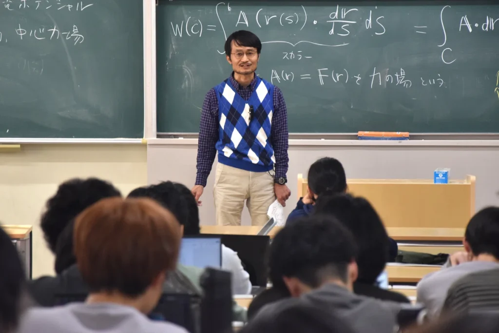 Professor Tanimura stands in front of rows of students in the lecture hall. 