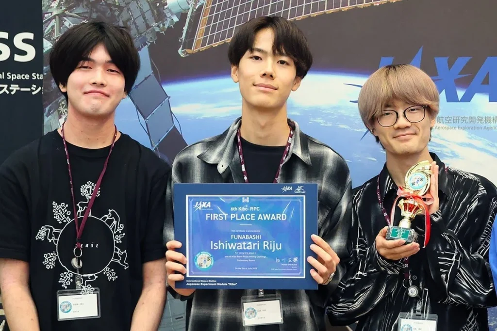 Ishiwatari is pictured with the other two members of his team. Ishiwatari stands in the middle, holding an award.