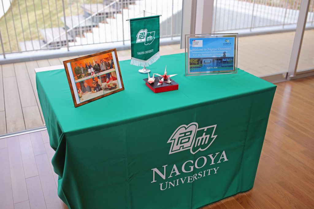 A table with framed photographs of the agreement signing ceremony in Tokyo on April 1, 2026, and origami cranes made with paper patterned after the Japanese and French flags. 