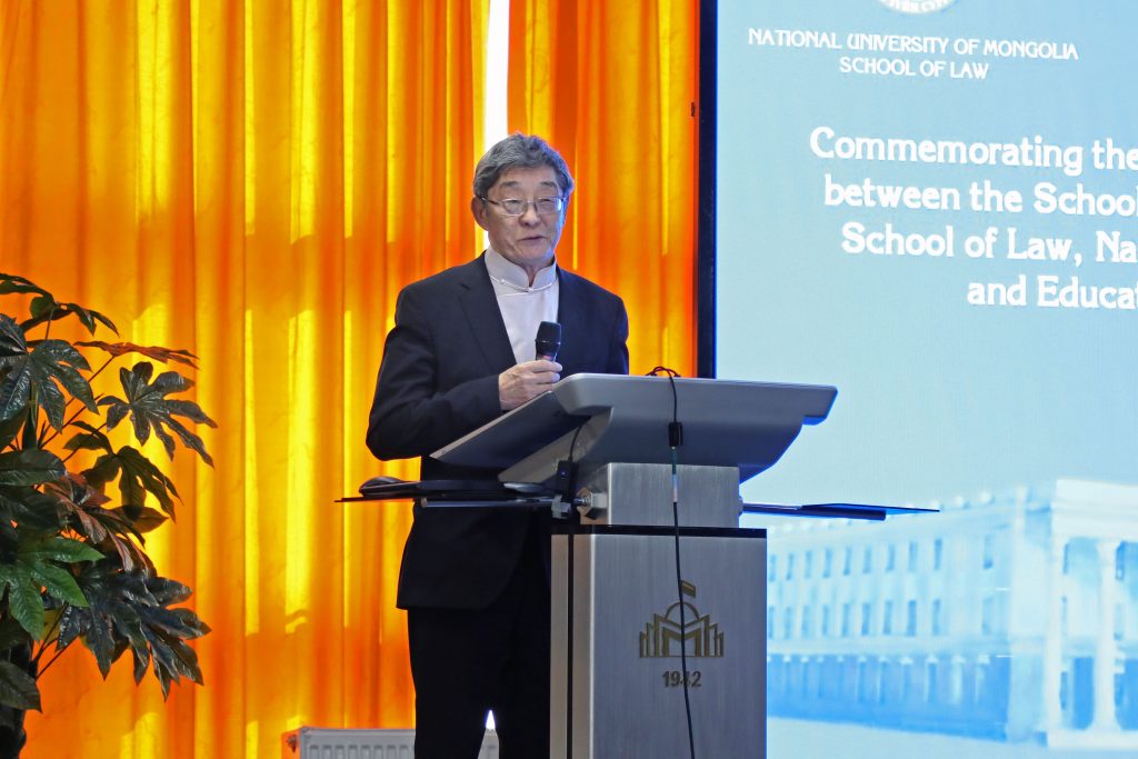 Professor Narangerel Sodovsuren stands at a podium on stage and gives his remarks.
