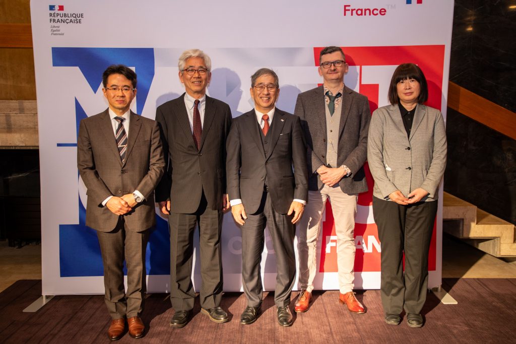 A group of five faculty members from Nagoya University, Gifu University, and CNRS stand in front of a banner resembling the French flag.