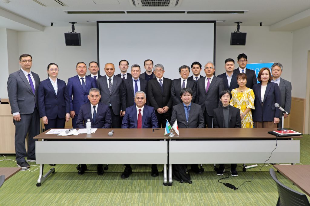 The visiting delegation and Nagoya University faculty members stand at the front of the room for a group photo.