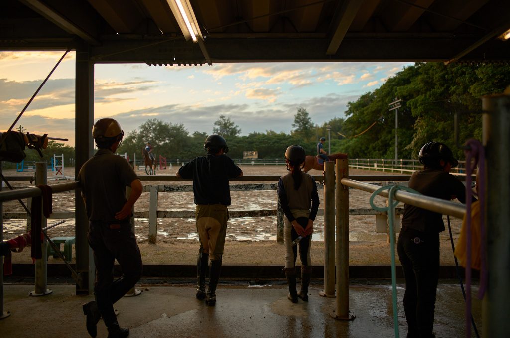 Students stand on the outer perimeter of the training course watching others practice