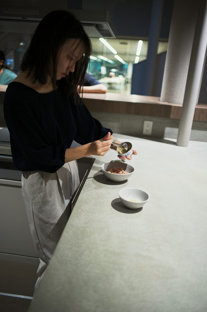 Student transferring tuna from can to bowl