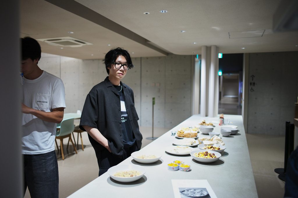Student stands near counter with prepared dishes waiting for the tasting session