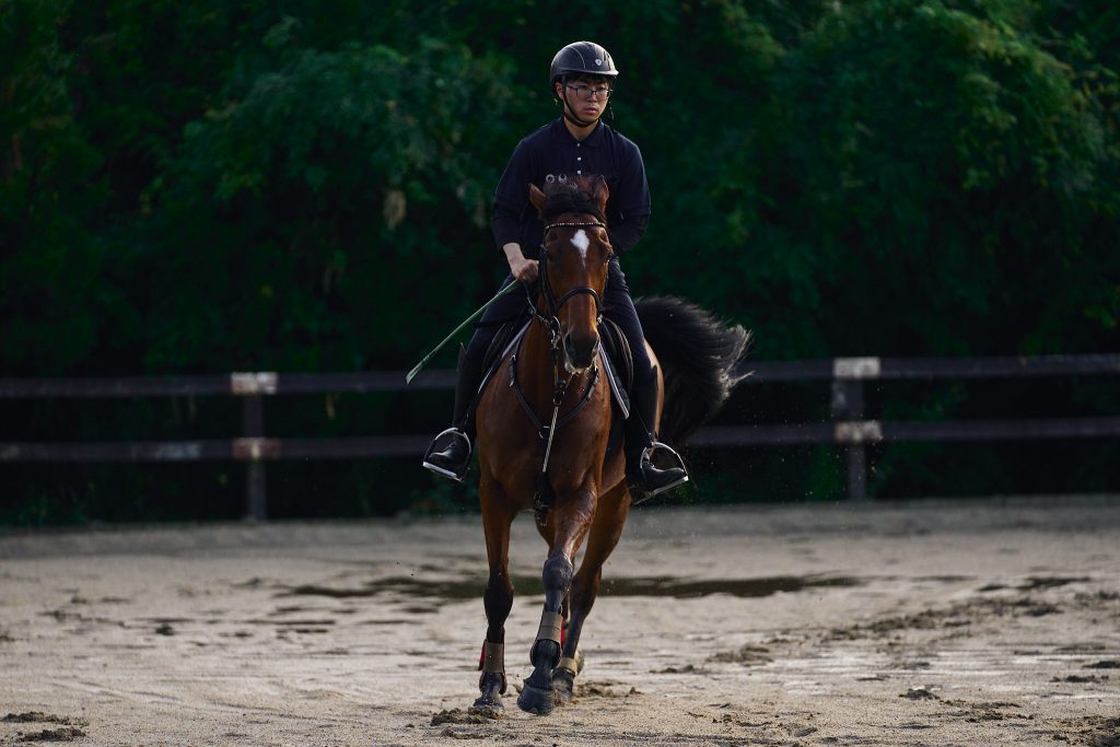 A student jogs the horse on the wet training grounds after a rain