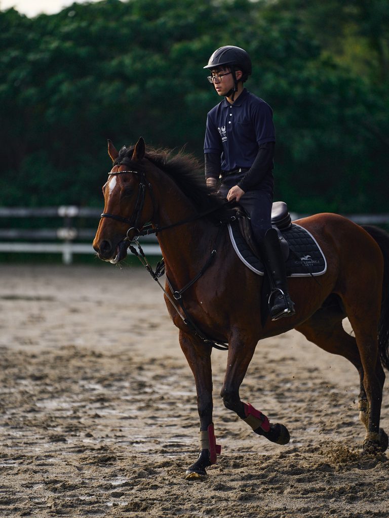 A student jogs the horse on the wet training grounds after a rain