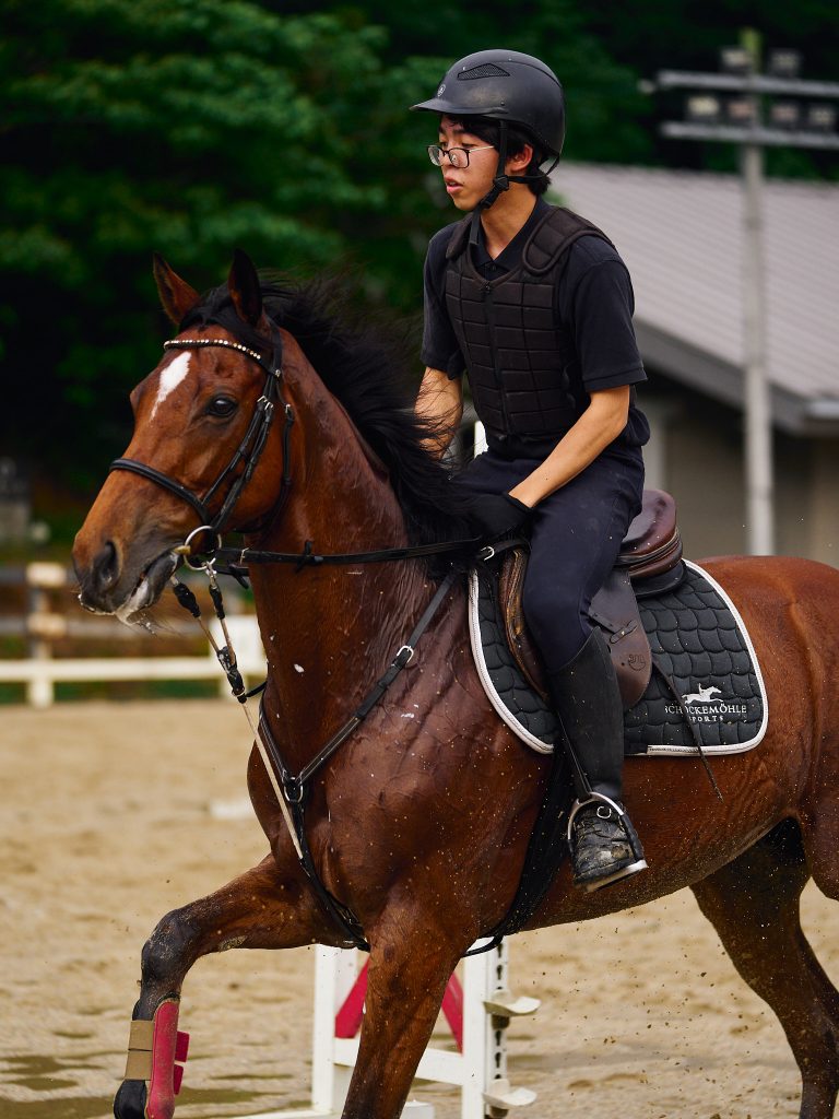 A student jogs the horse on the wet training grounds after a rain