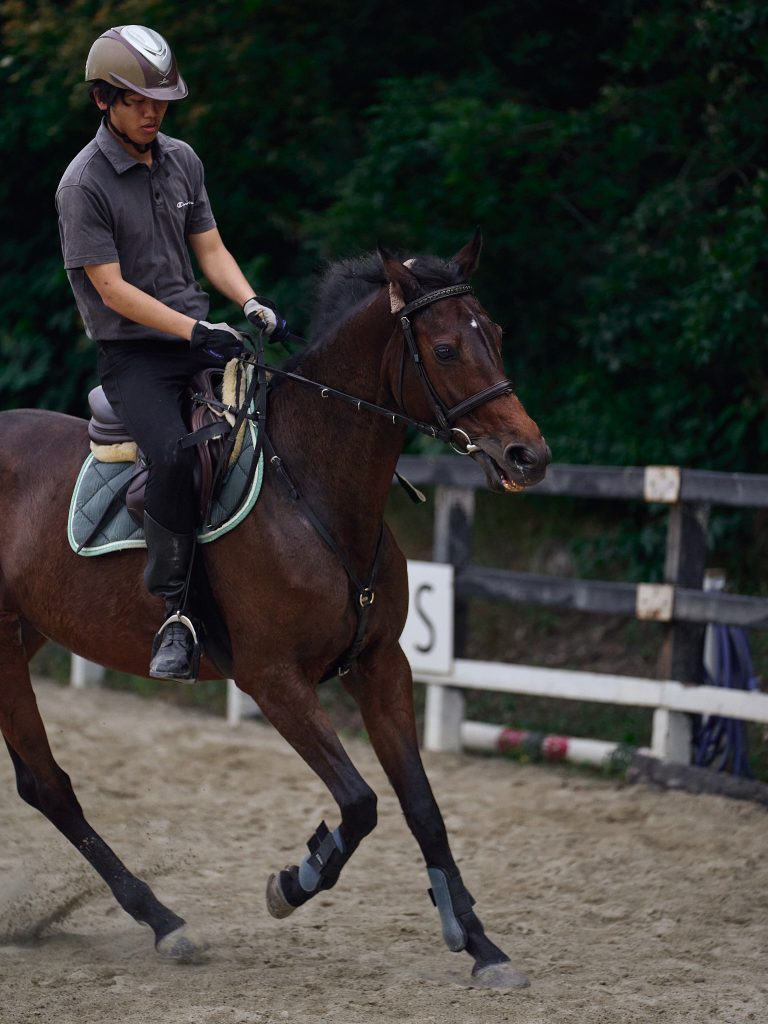 A student jogs a club horse around the training course