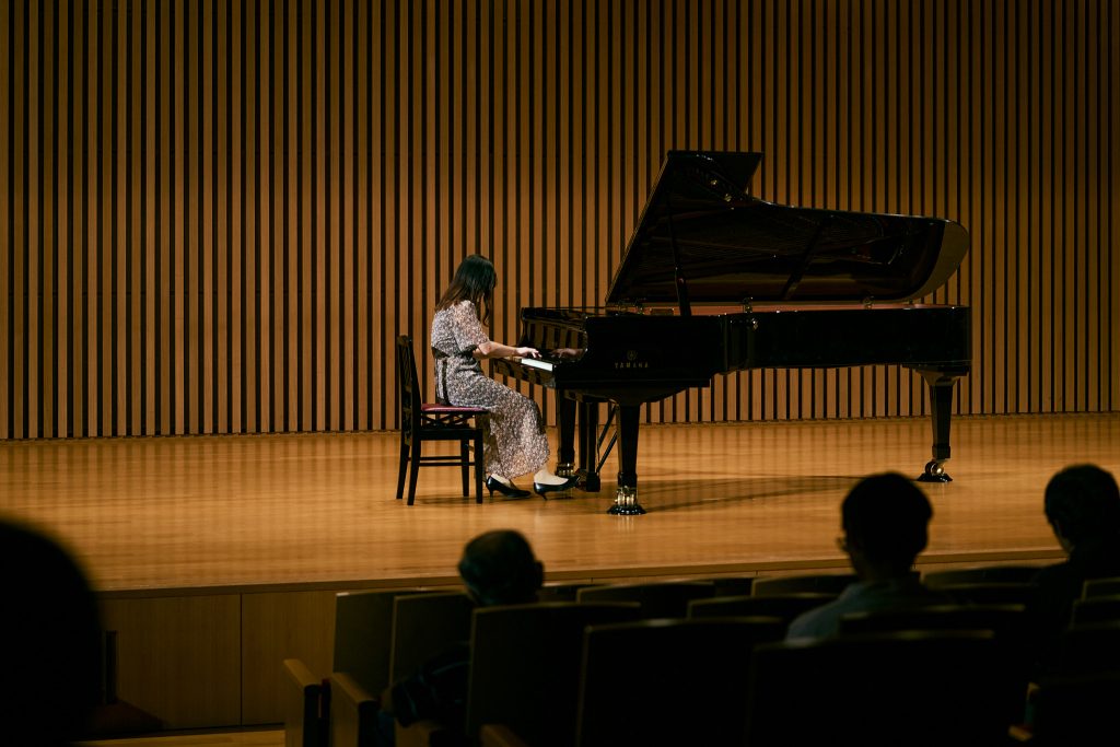 Student plays a piano on stage in the Toyoda Auditorium during the Nagoya University